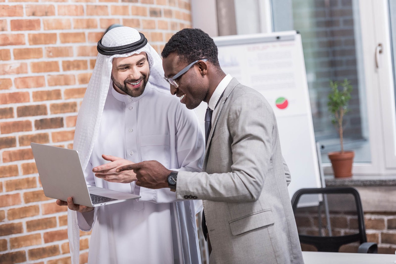 Multiethnic businessmen pointing at laptop in office